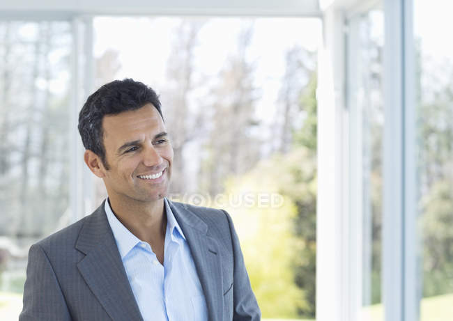 Hombre de negocios caucásico sonriendo en la oficina moderna - foto de stock