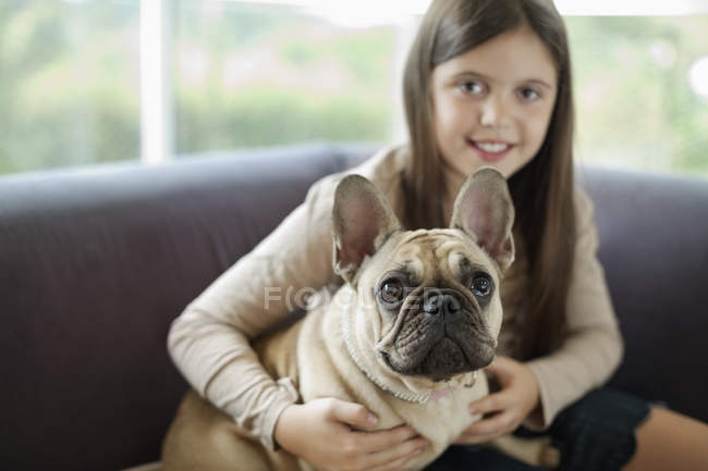 Дівчина розслабляє собаку на дивані в сучасному будинку — стокове фото