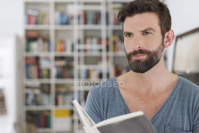 Hombre leyendo libro en la sala de estar - foto de stock