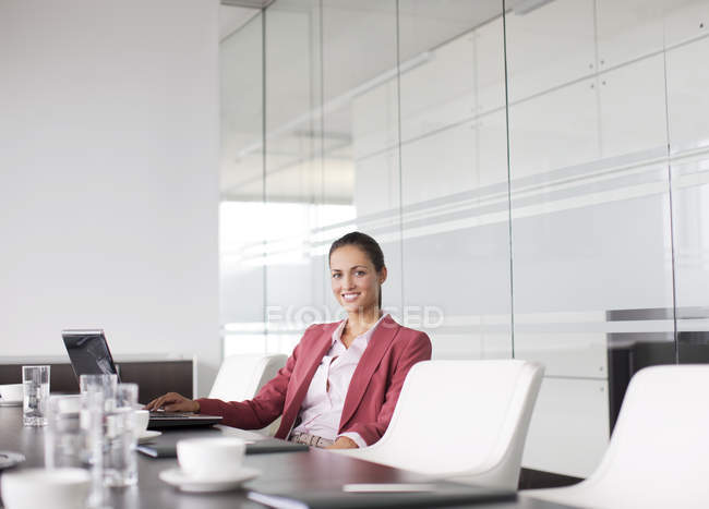 Mujer de negocios sonriendo en la mesa de reuniones en la oficina moderna - foto de stock