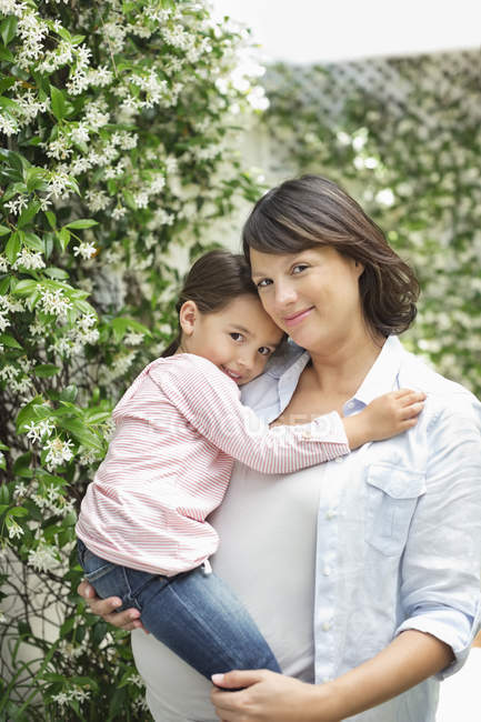 Pregnant mother holding daughter outdoors — Stock Photo