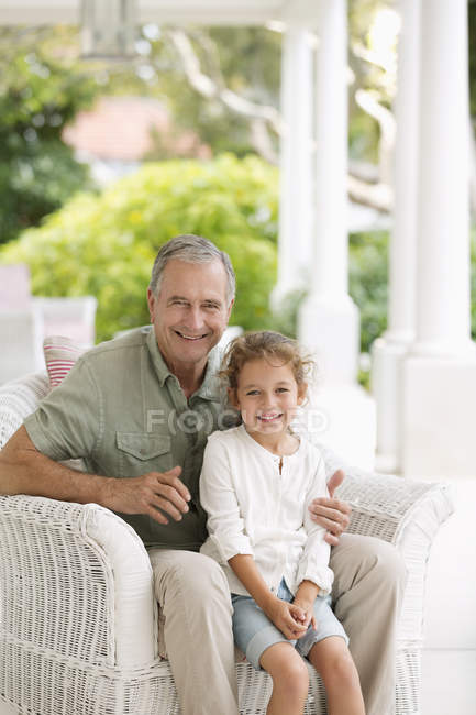 Щасливий старший чоловік з онукою на ганку — стокове фото