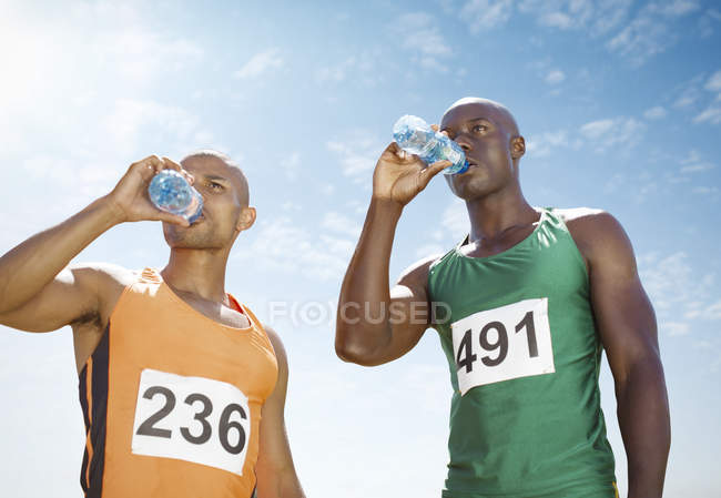 Бегуны пьют воду на трассе — стоковое фото