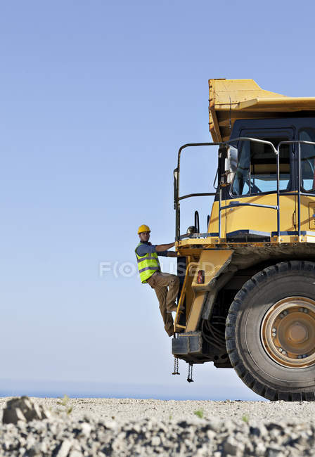 Worker climbing machinery in quarry — Stock Photo