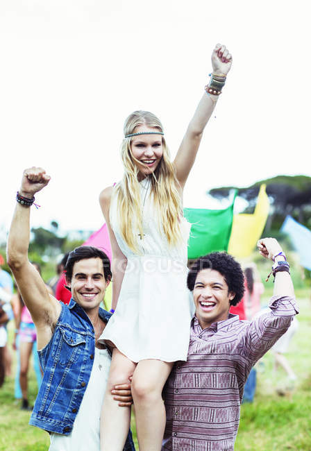 Portrait of men carrying woman at music festival — Stock Photo