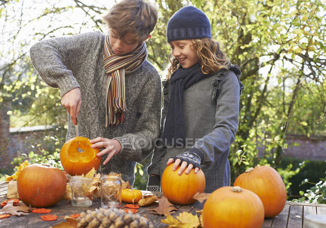 Children carving pumpkins together on outdoor table — Stock Photo