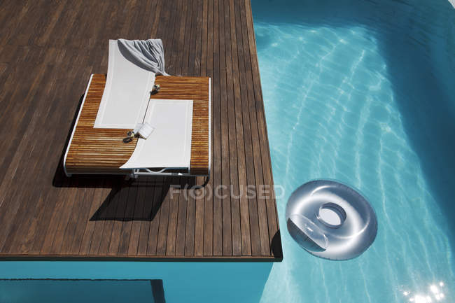 Lounge chairs on deck at luxury poolside — Stock Photo