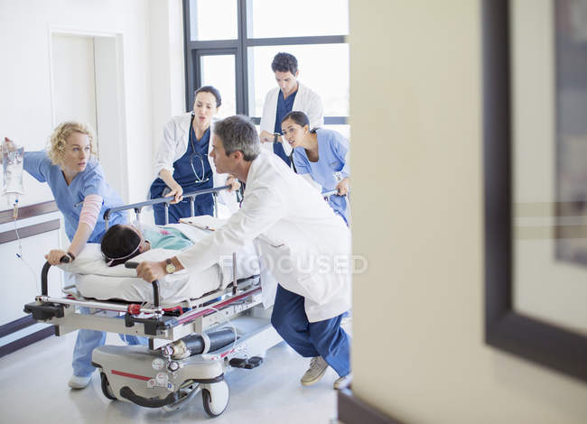 Врачи и медсестры спешат на носилках по больничному коридору — стоковое фото