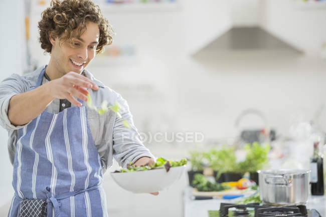 Человек делает салат на кухне — стоковое фото