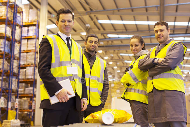Бизнесмен и рабочие улыбаются на складе — стоковое фото