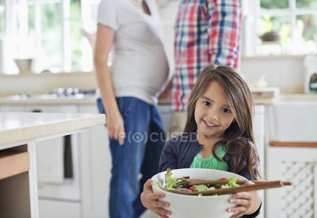 Girl holding bowl of salad in kitchen — Stock Photo