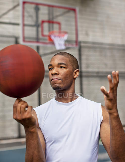 Чоловік обертається баскетболом на пальці в суді — стокове фото
