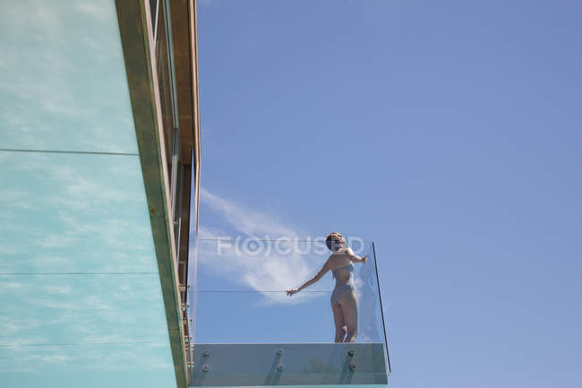 Woman with arms outstretched on modern balcony — Stock Photo
