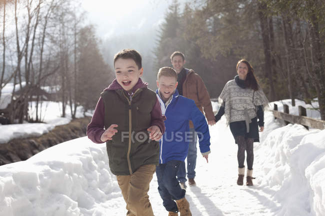 Familia feliz corriendo en carril nevado - foto de stock