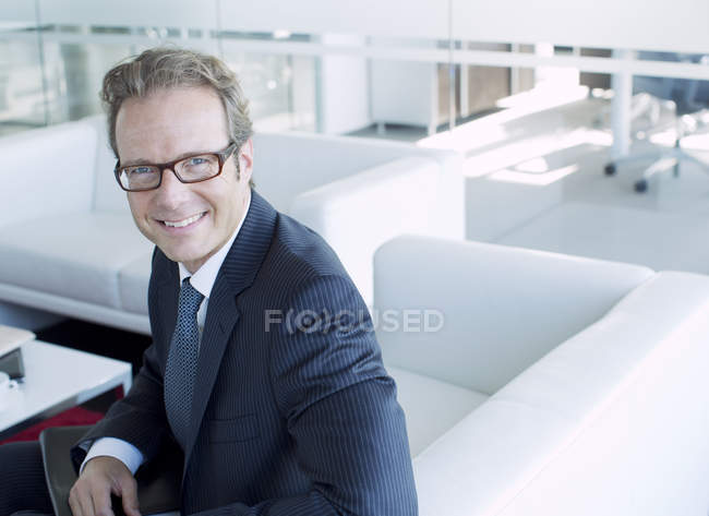 Бизнесмен улыбается в вестибюле современного офиса — стоковое фото