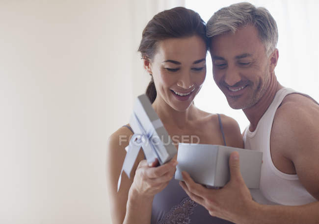 Sonriente pareja abriendo caja de regalo - foto de stock