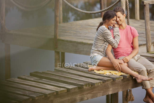 Прихильна пара сидить на причалі над озером — стокове фото