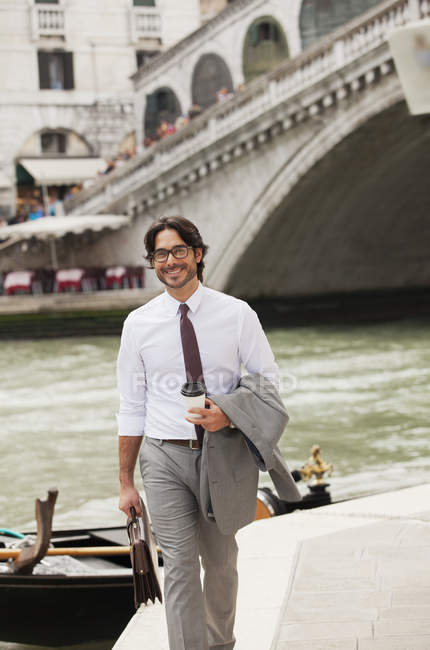 Портрет улыбающегося бизнесмена с кофе, гуляющего по каналу в Венеции — стоковое фото