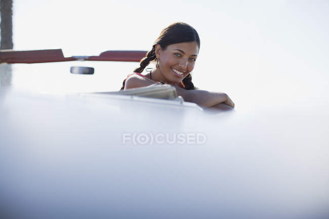 Mulher sorridente inclinada para fora do conversível — Fotografia de Stock