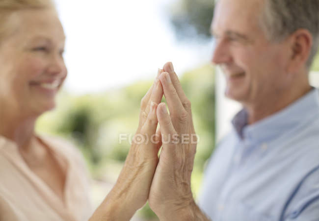 Старша пара торкається рук на патіо — стокове фото