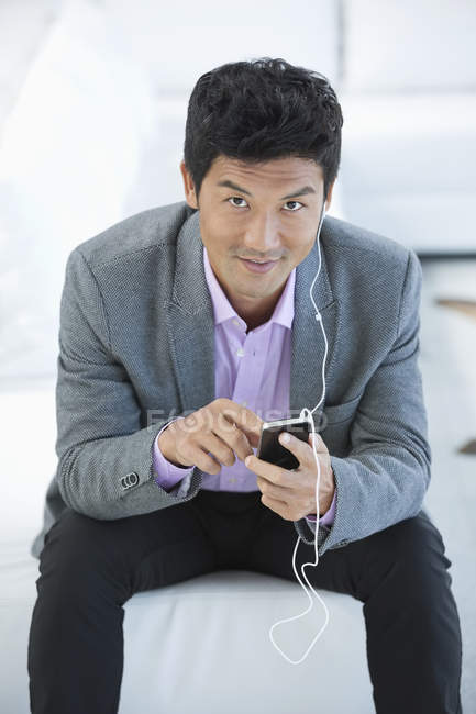 Businessman listening to headphones on sofa at modern office — Stock Photo