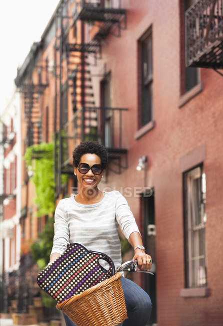 Woman riding bicycle on city street — Stock Photo