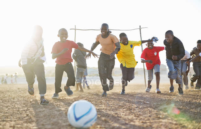 Boys playing soccer together in dirt field — Stock Photo