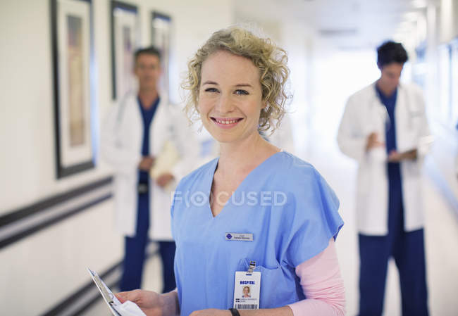 Retrato de enfermera sonriente en el pasillo del hospital - foto de stock