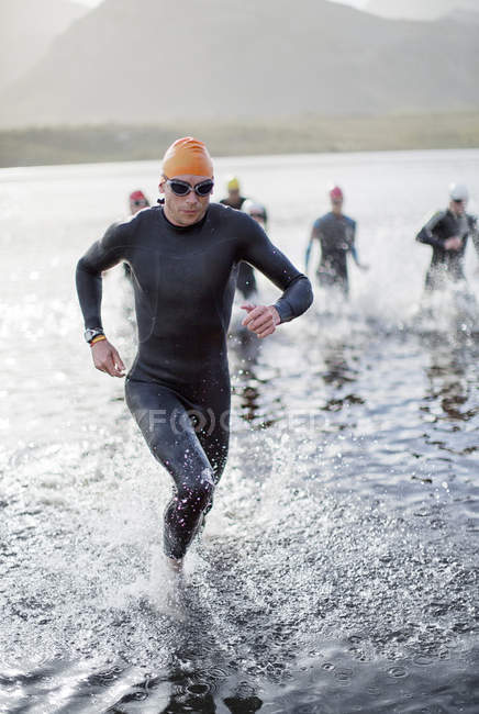 Triatletas confiantes e fortes emergindo da água — Fotografia de Stock