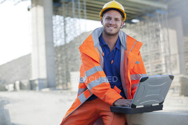 Trabajador usando el ordenador portátil en el sitio - foto de stock