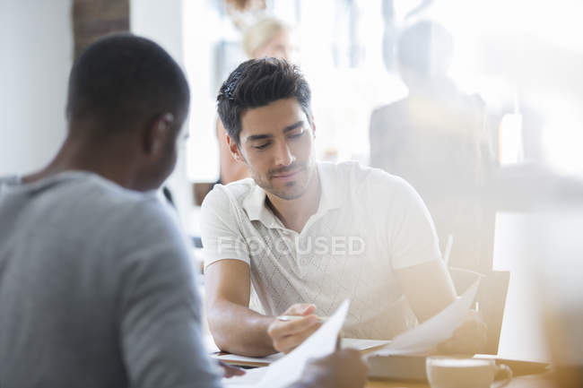 Empresários olhando através de documentos no café juntos — Fotografia de Stock