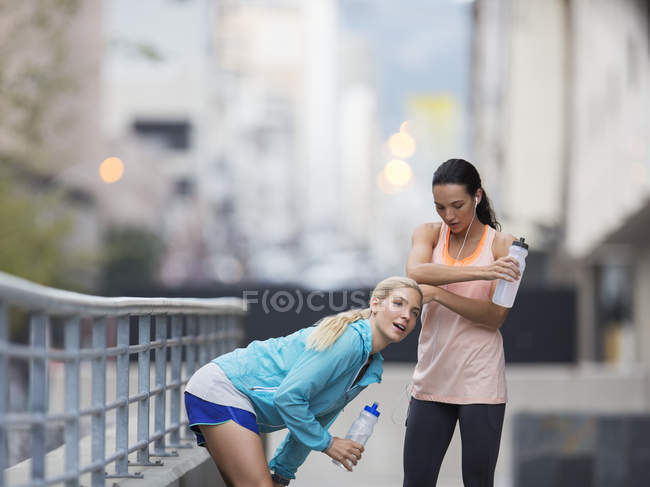 Mujeres descansando después de hacer ejercicio en la calle de la ciudad - foto de stock