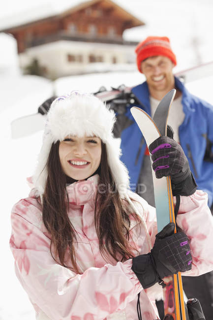 Retrato de pareja sonriente con esquís fuera de la cabina - foto de stock