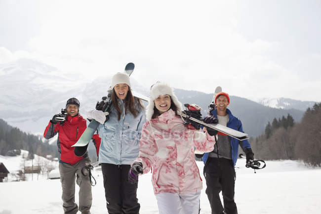 Enthusiastic friends with skis in snowy field — Stock Photo