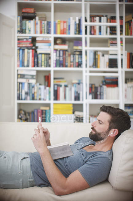 Homme écoutant de la musique sur canapé — Photo de stock