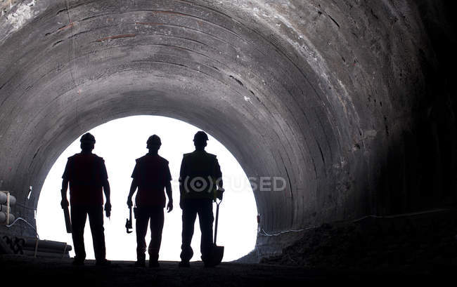 Silueta de los trabajadores en túnel - foto de stock