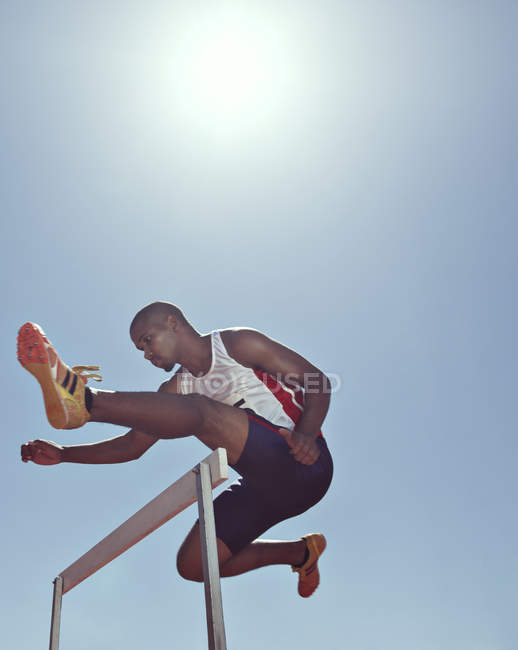 Track and field athlete clearing hurdle — Stock Photo