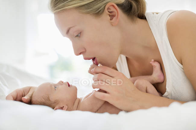 Mother cradling newborn infant on bed — Stock Photo