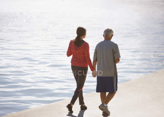 Старшая пара, гуляющая вместе по пляжу — стоковое фото
