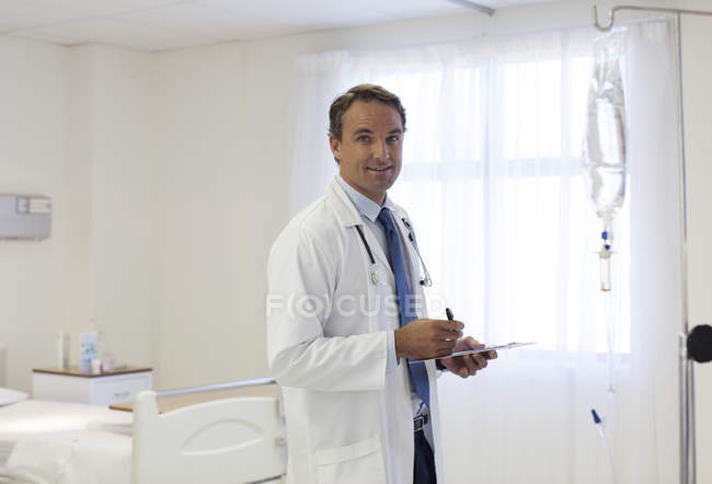 Arzt schreibt auf Klemmbrett in modernem Krankenhaus — Stockfoto