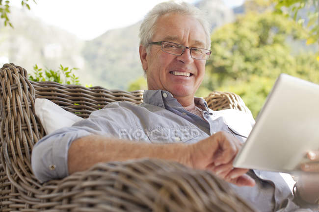 Retrato del hombre sonriente usando tableta digital en el patio - foto de stock