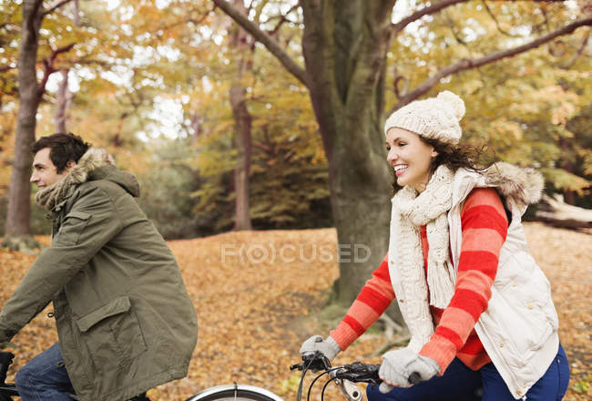 Pareja feliz montando bicicletas en el parque - foto de stock