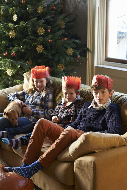 Happy children in paper crowns sitting on sofa — Stock Photo