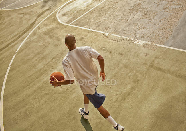 Hombre jugando baloncesto en la cancha - foto de stock