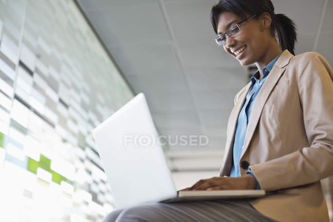 Femme d'affaires utilisant un ordinateur portable au bureau moderne — Photo de stock