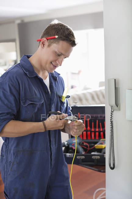 Skillful caucasian electrician working on telephone in home — Stock Photo