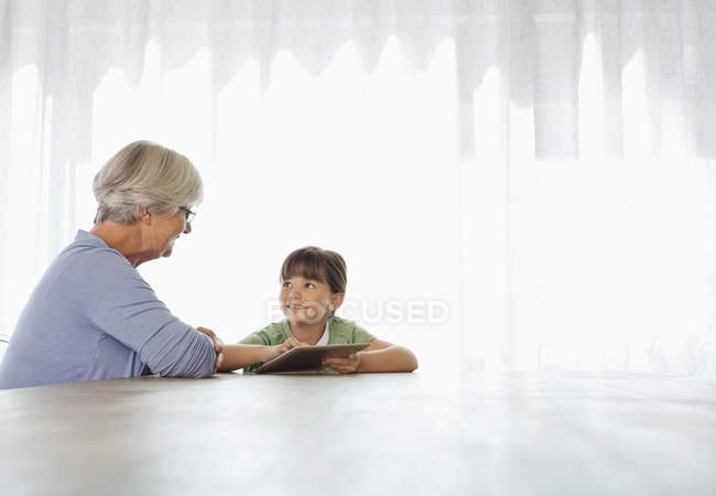 Mujer mayor y nieta usando tableta - foto de stock