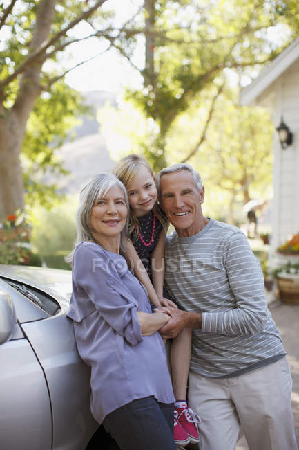 Casal mais velho e neta apoiando-se no carro — Fotografia de Stock