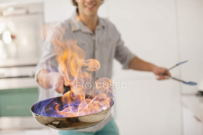 Uomo cucina con fuoco in cucina — Foto stock
