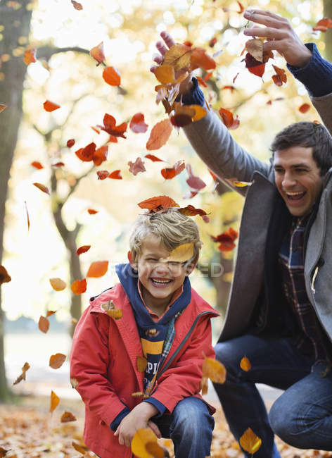 Père et fils jouant dans les feuilles d'automne — Photo de stock